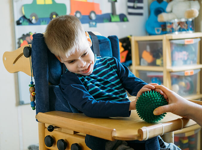 A young boy with a disability in a high chair.